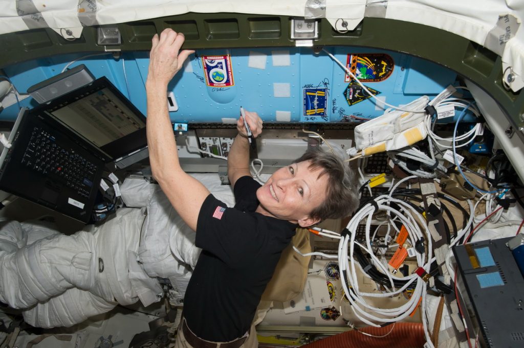 iss050e054558 (03/05/2017) --- NASA astronaut Peggy Whitson signs a bulkhead on the International Space Station next to the Expedition 50 crew patch.